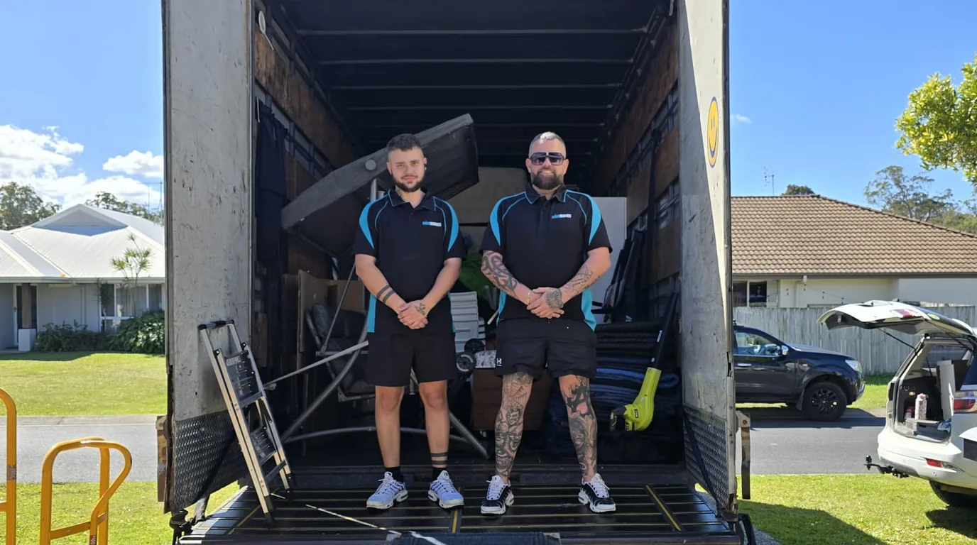 The Mint Movers crew in the back of a loaded removals truck outside a Gold Coast home